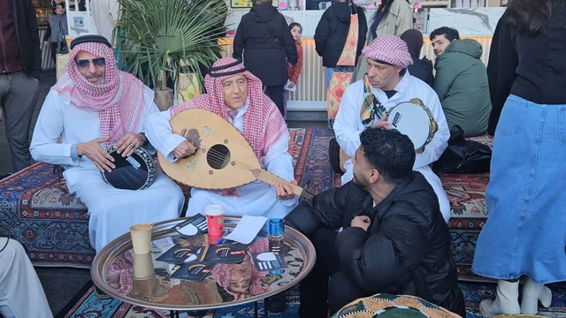 Drie zittende muzikanten spelen samen op een oed en percussie-instrumenten