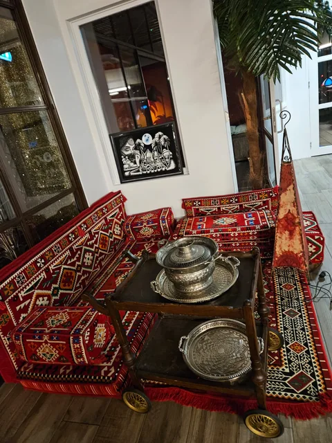 Zilverkleurig theeservies op een lage tafel voor een rood gedecoreerde loungebank